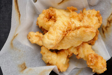 Fried chicken nuggets on paper, on a dark background
