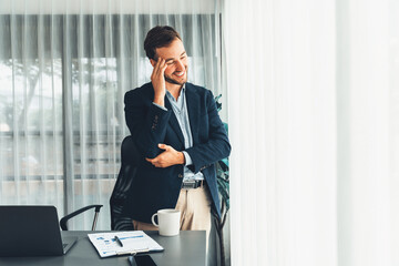 Handsome businessman in black suit stand confidently in his modern office portrait, deep in thought...