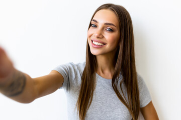 Portrait of a smiling woman making selfie photo on smartphone isolated on a white background
