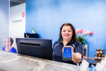 receptionist holding out EFTPOS machine for taking card payment for professional services