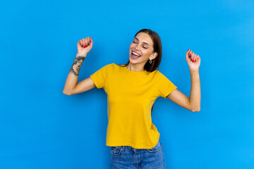 Portrait of satisfied glad funny woman eyes closed raise fists up isolated on blue color background