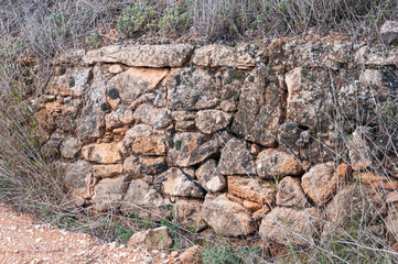 a stone fence made by a man in a field close-up, there is a place for an inscription. dry grass around