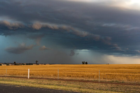 Rain falling from a colourful dramatic stormfront over a rural scene