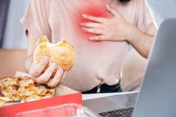 woman suffering from acid reflux , heartburn after over eating junk food, pizza and burger - obrazy, fototapety, plakaty