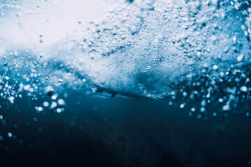 Wave underwater and surfer on surfboard in ocean. Underwater crashing wave and surfboard in...