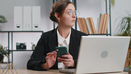 Young business woman playing on smartphone exciting mobile application celebrate winning racing, shooter game at office desk workplace. Professional manager freelancer girl enjoy good work of new app