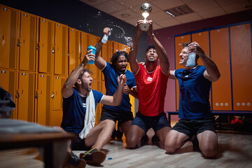Group of men in dressing room celebrating victory holding gold medal and feeling joyful, shouting...