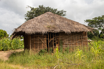 Fototapeta na wymiar Typical rural mud-house in remote village in Africa with thatched roof, very basic and poor living conditions for local population
