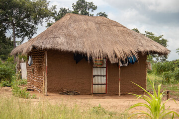 Fototapeta na wymiar Typical rural mud-house in remote village in Africa with thatched roof, very basic and poor living conditions