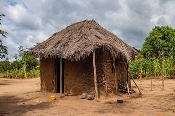 Typical rural mud-house in remote village in Africa with thatched roof, very basic and poor living...