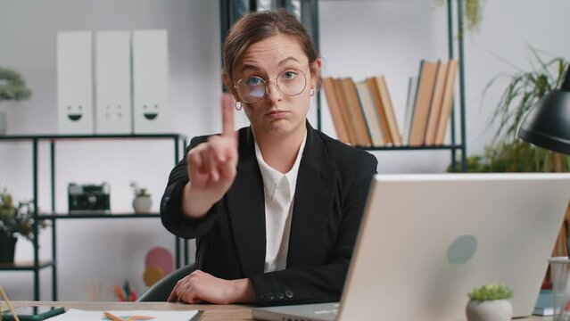 Caucasian young business woman working on laptop computer shakes finger, saying No be careful scolding and giving advice to avoid danger mistake disapproval sign at office. Confident freelancer girl
