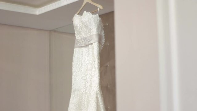 Beautiful expensive wedding dress in bedroom hanging on hanger