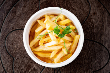 Salted French fries in white bowl on a wooden table