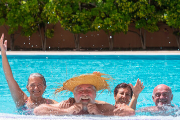 Cheerful group of senior family people friends laughing have fun in swimming pool together. Couples...