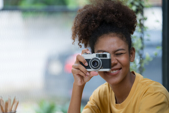 A beautiful mixed race African American girl taking photos with a retro film camera.