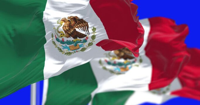Three Mexican national flags waving in the wind isolated on blue background