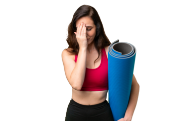 Young sport woman going to yoga classes while holding a mat over isolated background with tired and sick expression