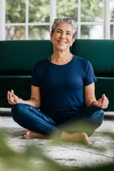 Foto op Canvas Enjoying yoga meditation: Serene senior woman smiling while meditating in lotus position © (JLco) Julia Amaral