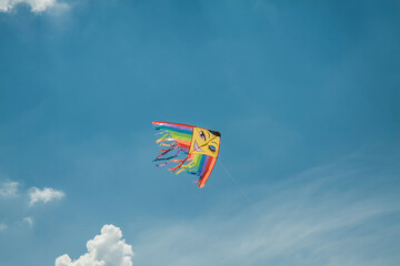 A rainbow-colored kite soars high in the sky, its vibrant hues representing LGBT colors