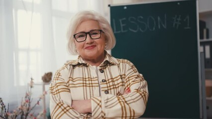Portrait of confident senior woman near chalkboard, school teacher occupation