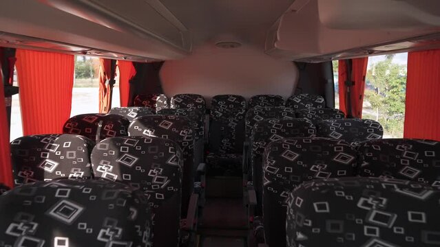 Back motion in the cabin of a large empty passenger bus between the rows of comfortable velvet seats