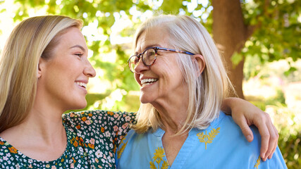 Multi-Generation Family With Senior Mother Wearing Glasses  And Adult Daughter Laughing In Garden 