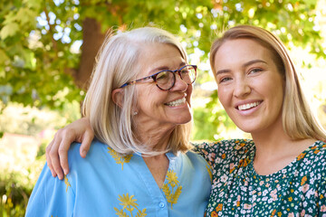 Multi-Generation Family With Senior Mother Wearing Glasses  And Adult Daughter Laughing In Garden 