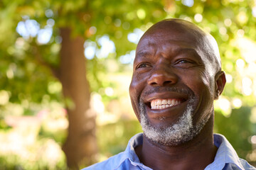 Portrait Of Smiling Senior Man Standing Outdoors In Garden Park Or Countryside