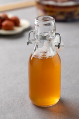 Glass bottle with homemade Japanese ume su, plum vinegar, close up and preserved umeboshi   