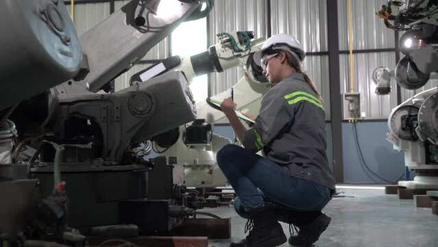Mechanical engineers with robotic welder., Programming development technology work. Female industrial engineer working at automated AI robotic production factory..	
