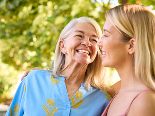 Multi-Generation Family With Senior Mother And Adult Daughter Laughing In Garden 