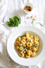 Concetto di cibo italiano. Gnocchi con crema di gorgonzola e noci su sfondo bianco. Vista dall'alto.