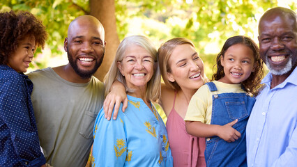 Portrait Of Multi-Generation Family Standing In Garden Smiling At Camera