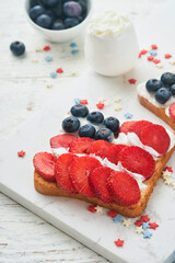 4th of July American Independence Day food. American flag sandwich with strawberries, blueberries, whipped sweet cream, soft cheese on toast bread. Independence or Patriotic Day breakfast idea Mock up