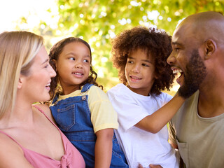 Portrait Of Multi-Racial Family Standing In Garden Smiling At Camera