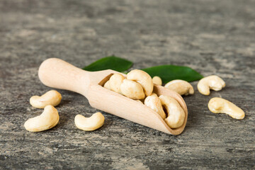 Cashew nuts with green leaves in spoon on table background, Healthy food