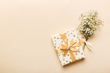 Gift or present box and flower gypsophila on light table top view. Greeting card. Flat lay style...