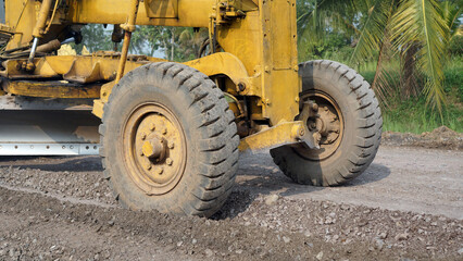 Fototapeta na wymiar close up of motor grader tires leveling stones and gravel for road repairs in Lampung 