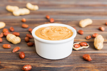 Bowl of peanut butter and peanuts on table background. top view with copy space. Creamy peanut pasta in small bowl