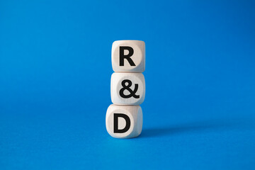 R and D - research and development symbol. Wooden cubes with word R and D. Beautiful blue background. Business and R and D concept. Copy space.