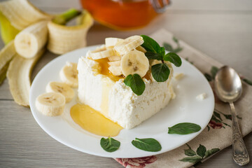 Portion of homemade milk curd with banana slices and honey