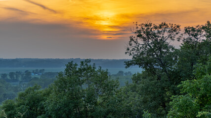 sunset over farmland in Kansas with trees in the foreground