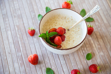 cooked diet oatmeal in a bowl with fresh ripe strawberries