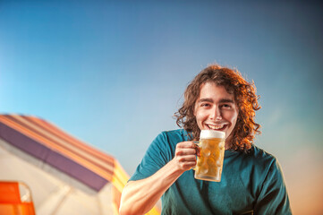 young man with glass of draft beer against sunset background