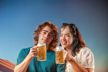 Interracial friends toasting draft beer against the sunset.