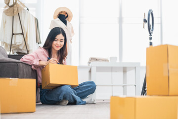 Asian woman packing parcel boxes, she owns an online store, she packs and ships through a private transport company. Online selling and online shopping concepts..