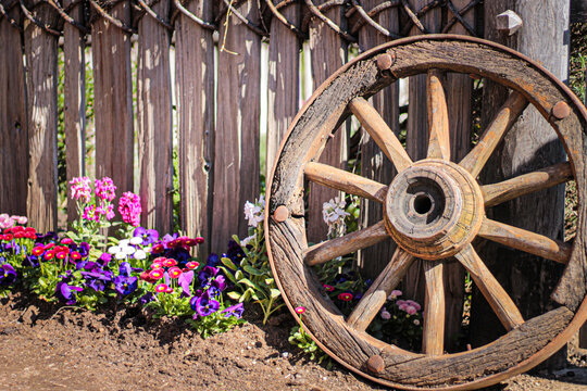 old wooden wagon wheel in a garden and a fence