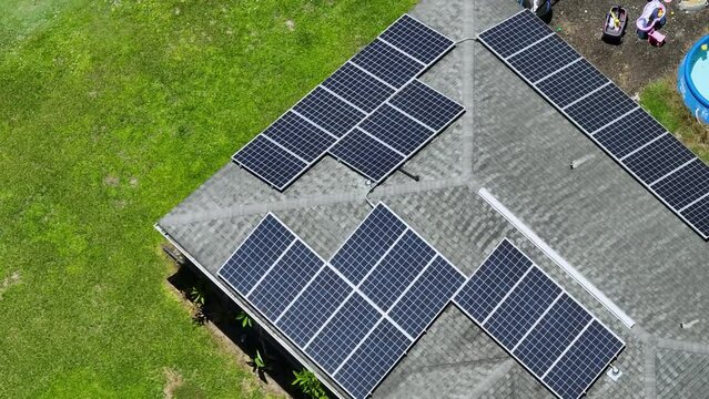 Ordinary residential house in USA with roof covered with solar panels for producing of clean ecological electricity in suburban rural area. Concept of investing in autonomous home for energy saving