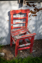 The red wooden chair has completed its life. Broken handmade wooden chair left to nature. Red broken wooden chair in idle condition.