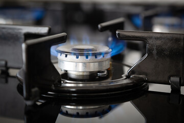 Gas cooker with burning flames of natural gas. Close up blue fire from domestic kitchen stove top....